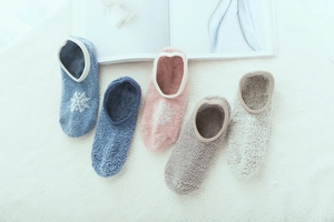 Assorted colors of thick coral fleece floor socks with snowflake embroidery on fuzzy rug