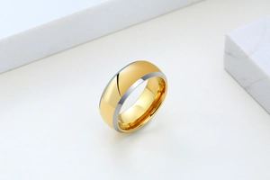 Close-up of polished two-tone gold and silver tungsten steel ring on marble base