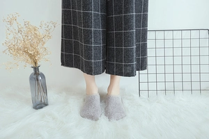 Close-up of grey coral fleece floor socks with non-slip silicone dots on a cozy carpet