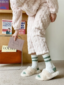 Detail of pink coral fleece socks with cable knit texture and fuzzy indoor slippers