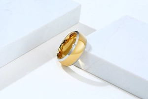Close-up of gold tungsten ring with silver beveled edges and polished mirror finish