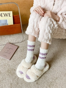 Close-up of cozy coral fleece striped socks and plush slippers for winter indoor wear