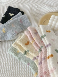 Detailed view of colorful thick coral fleece socks with heart patterns on white knit