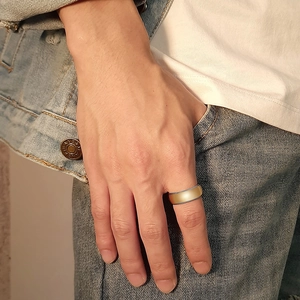 Close-up of matte gold tungsten ring for men worn on finger with casual background