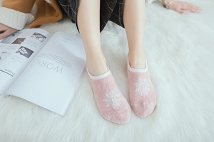 Close-up of pink coral fleece floor socks with white snowflake pattern and non-slip sole