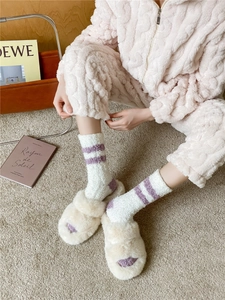 Close-up of white coral fleece socks with purple stripes and thick plush cable knit texture