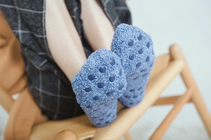 Close-up of blue fuzzy coral fleece baby floor socks with anti-slip silicone grippers