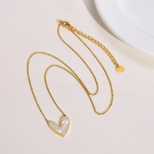 Collier cœur doré avec incrustation de nacre blanche sur fond blanc minimaliste