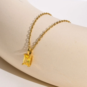 Macro shot of rectangular yellow zircon pendant on a golden stainless steel chain