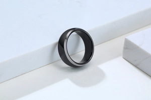 Close-up of a polished black tungsten ring resting on a luxury white marble surface