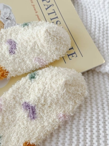 Detailed macro texture of cream white coral fleece socks with colorful heart patterns