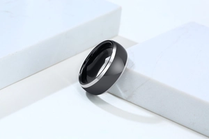 Close-up of minimalist black tungsten men's ring with silver edges on marble blocks