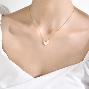 Collier cœur doré avec incrustation en nacre porté par un mannequin pour un look chic