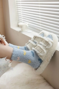 Close-up of heart pattern coral fleece socks and plush slippers in a cozy home setting