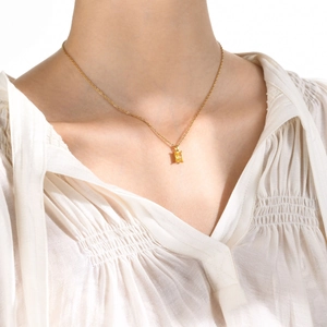 Close-up of a gold stainless steel necklace with a rectangular yellow zircon pendant