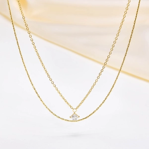 Dettaglio di una collana a doppio strato in oro con pendente in zircone quadrato