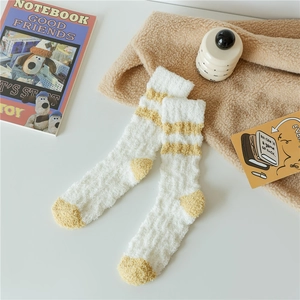 Detailed texture of thick coral fleece socks with yellow stripes in a cozy home setting