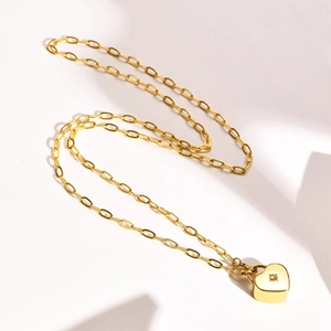 Détail macro du collier chaîne trombone doré avec pendentif cœur gravé d'une étoile