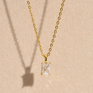 Macro shot of rectangular clear zircon pendant with four-prong setting on gold chain