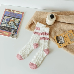 Close-up of thick coral fleece socks with pink stripes and cozy plush texture