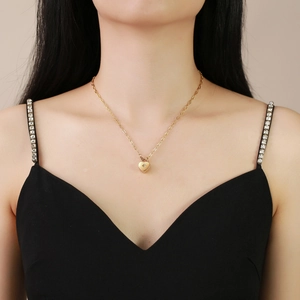 Détail d'un collier doré avec pendentif cœur et zircon en étoile sur chaîne fine