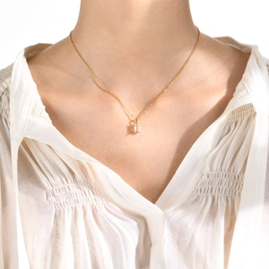 Detail of a minimalist gold necklace with a rectangular clear zircon pendant on model