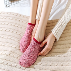 Pink coral fleece thermal socks for winter with red hem on warm knitted blanket