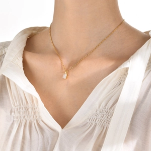 Close-up of a gold necklace featuring a rectangular clear zircon pendant on model