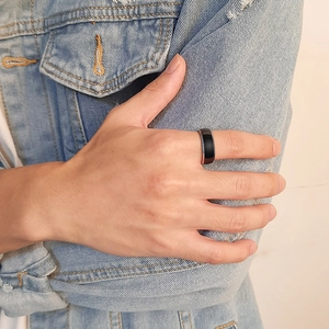 Minimalist black and silver tungsten steel ring worn on a man's finger with denim jacket