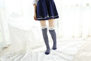 Détail de chaussettes montantes en polaire corail à rayures bleues et blanches avec ourson