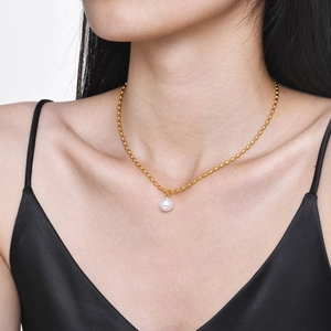 Close-up of a gold pearl pendant necklace worn by a model for a minimalist style look