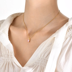 Elegant gold necklace with rectangular pink zircon pendant worn on a female model