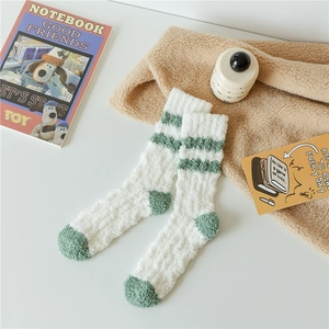 Close-up of white and green striped coral fleece socks with warm textured winter fabric
