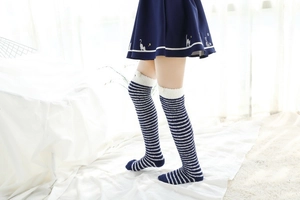 Détail de chaussettes hautes rayées en polaire corail avec pompons blancs décoratifs