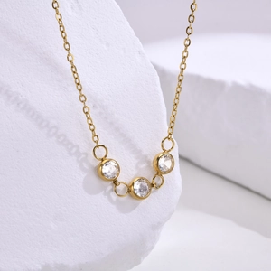 Vue macro d'un collier fin en acier inoxydable doré avec trois zircons blancs brillants