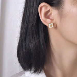 Détail des boucles d'oreilles rose vintage en or avec incrustation carrée en résine