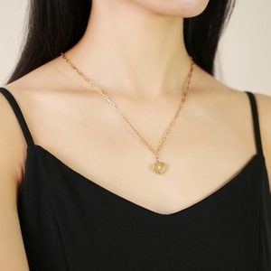 Détail d'un collier cœur doré avec incrustation d'étoiles sur une chaîne trombone porté