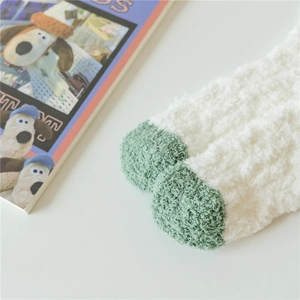 Close-up of thick coral fleece socks in cream and sage green for winter warmth