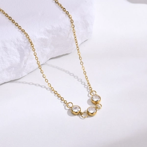 Gros plan détaillé d'un collier doré en acier inoxydable avec trois zircons blancs