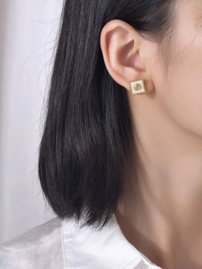 Vue macro de boucles d'oreilles vintage avec relief rose dorée sur oreille de femme
