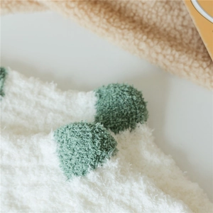 Close-up of thick coral fleece socks with white fluffy texture and green polka dots