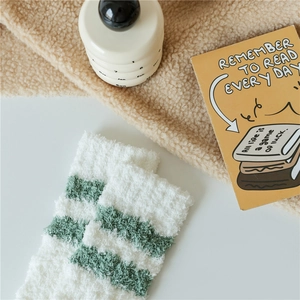 Close-up of thick green striped coral fleece socks on a cozy plush background