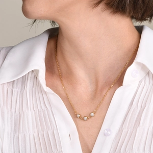 Collier fin en acier doré avec trois zircons blancs porté par un mannequin chic