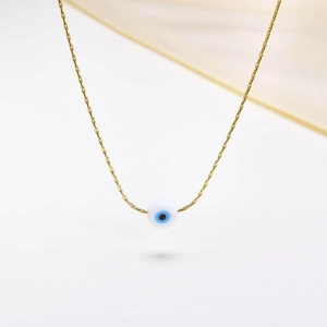 Close-up of golden Evil Eye pendant necklace with blue bead on clean white background