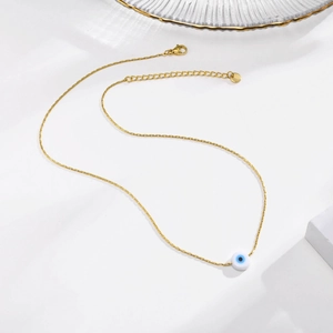 Detail view of gold evil eye necklace with lobster clasp and extension chain on white stone