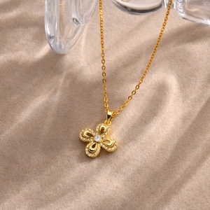 Macro detail of gold flower pendant with sparkling white cubic zirconia on beige sand