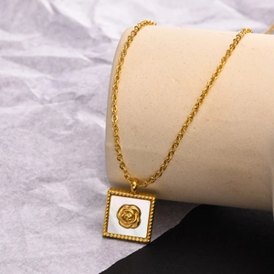 Détail d'un pendentif rose en nacre et acier doré sur un support à bijoux cylindrique