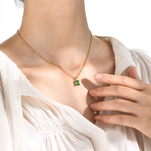 Detail of a minimalist gold chain featuring a rectangular emerald green zircon pendant
