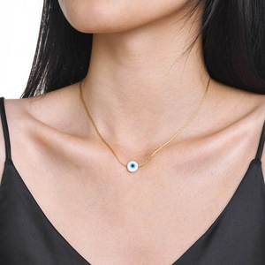 Gold stainless steel evil eye pendant necklace worn by a model on the collarbone