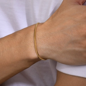 Minimalist gold square snake chain bracelet for men and women on a wrist with white shirt